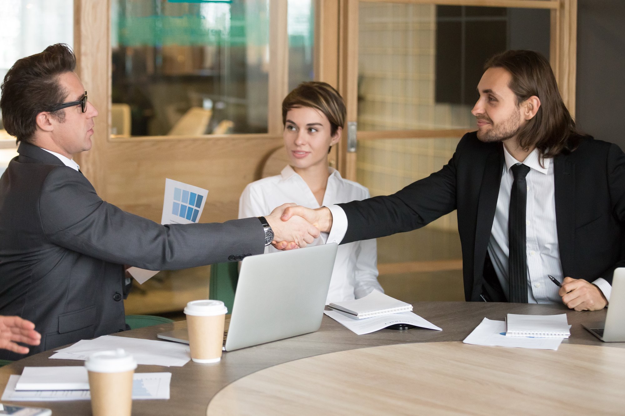 businessman-handshaking-new-colleague-during-team-meeting